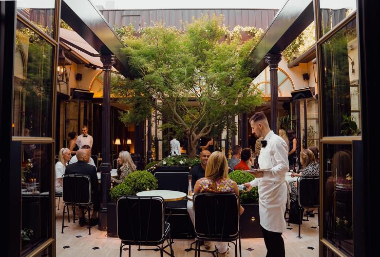 在屋顶露台 La Terrasse,一名服务生正为宾客提供服务。© Liana Hardy Photography 版权所有