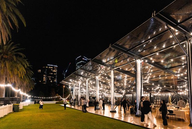 在玻璃幕墙环绕的 The Kingsman,由木质地板和草坪区构成的活动场地布置妥当,宾客云集。© The Kingsman 版权所有