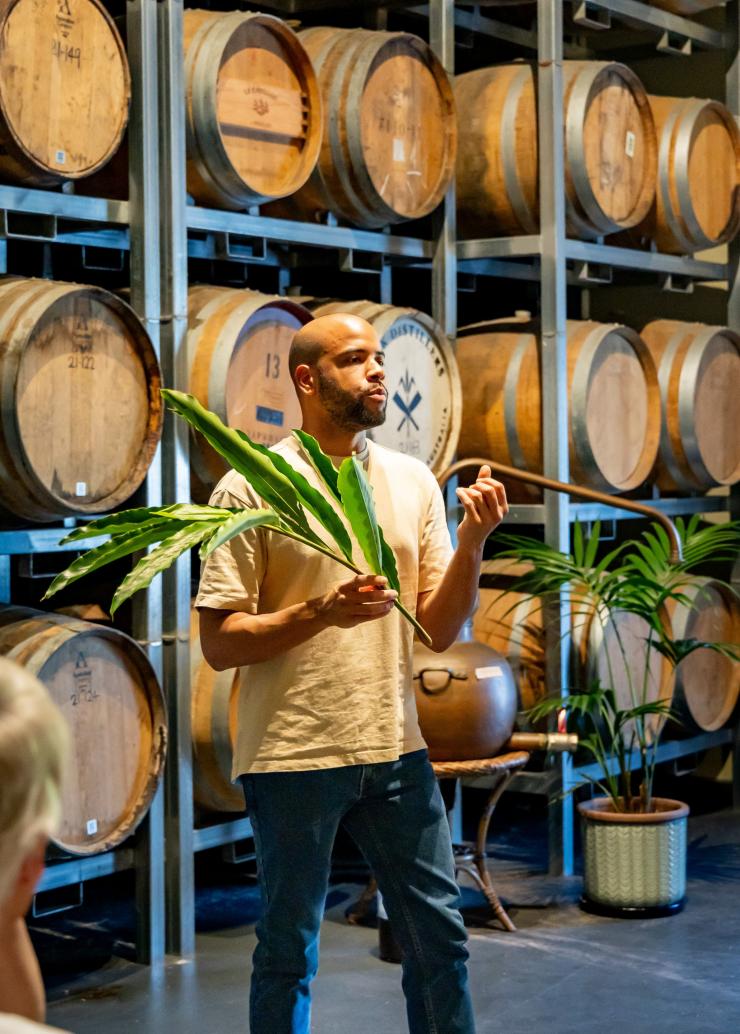 在酿酒厂里,Husk 酿酒师站在酒桶前为宾客进行讲解。© Husk 农场酿酒厂版权所有