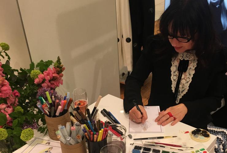 艺术家 Ange Rehe 在活动现场坐在桌旁,为与会代表们现场创作肖像画 © Angie Rehe 版权所有